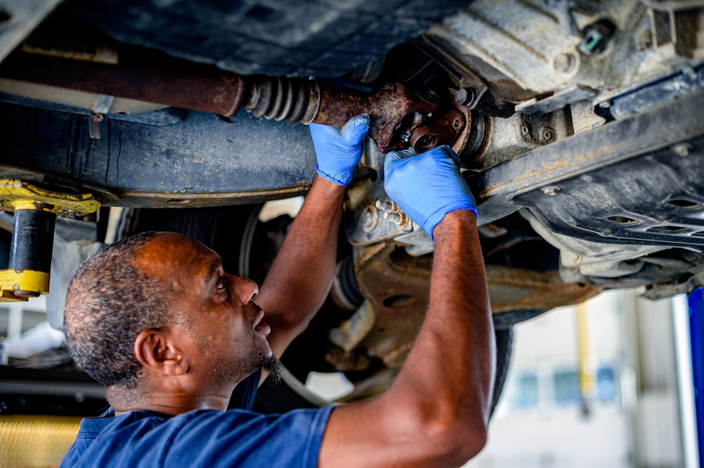 Mechanic in gloves working underneath a car on the brake system