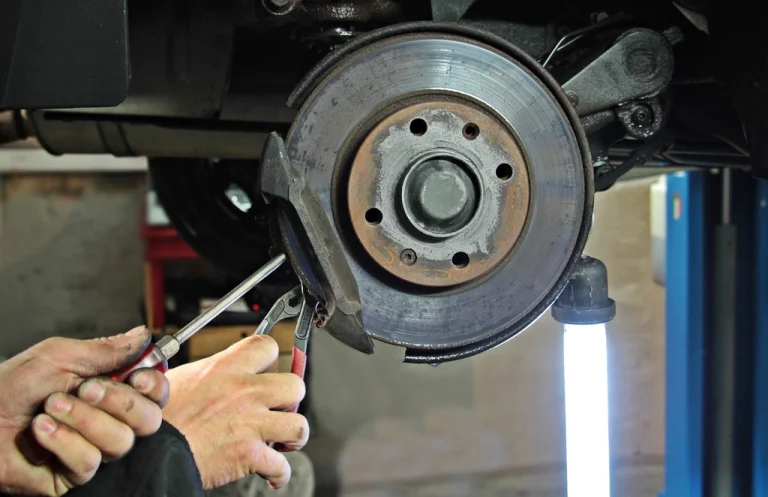Brake disc and caliper being inspected during a car brake repair