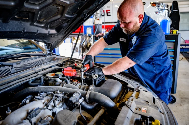 Two mechanics working in a car engine bay during a full service