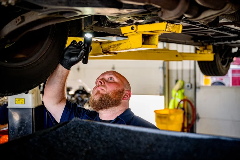 Mechanic checking components under a raised car during a major service