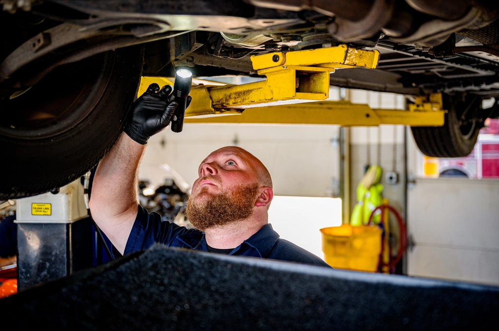 Mechanic checking components under a raised car during a major service