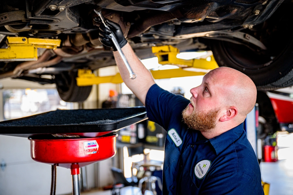 Mechanic inspecting the underside of a car on a lift during an MOT test in Bedford